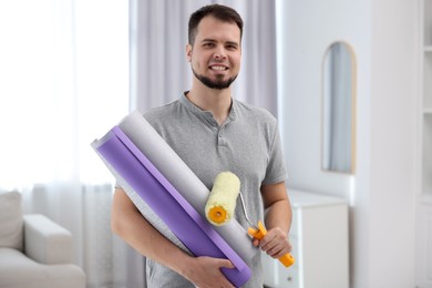 Man with wallpaper rolls and roller in room