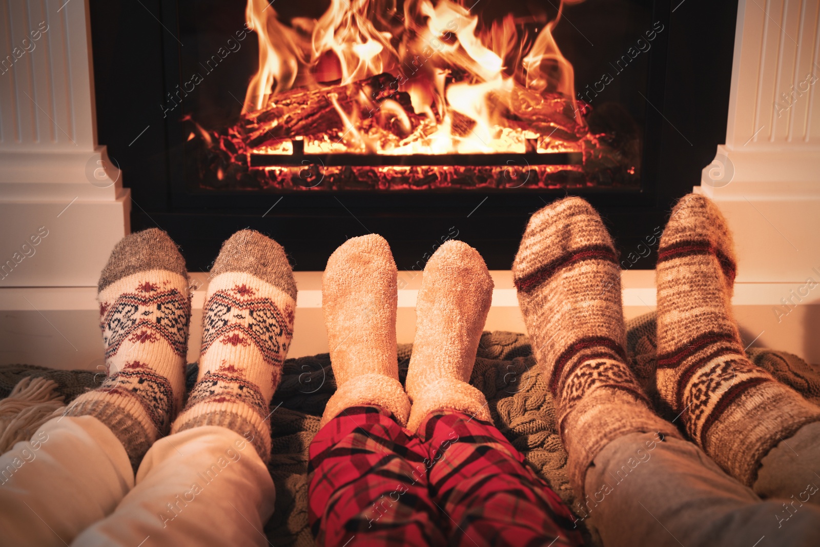 Photo of Lovely family in warm socks resting near fireplace at home, closeup