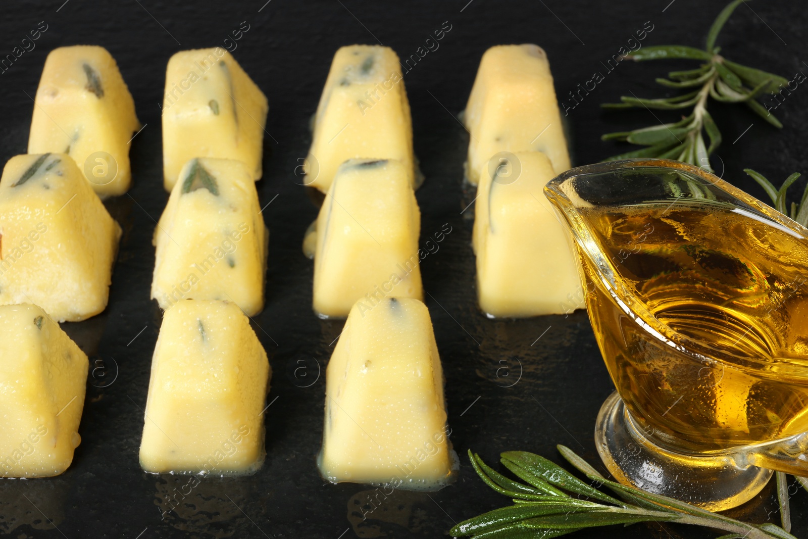 Photo of Rosemary and olive oil ice cubes on dark table