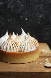 Photo of Tartlet with meringue on wooden board, closeup and space for text. Delicious dessert