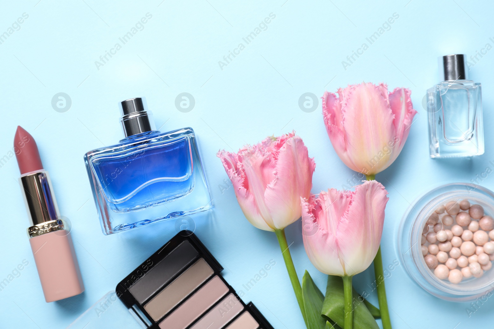 Photo of Flat lay composition with different makeup products and beautiful spring flowers on light blue background