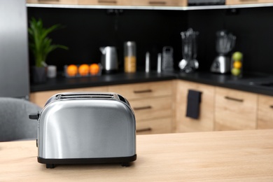 Photo of Modern toaster on table in kitchen, selective focus