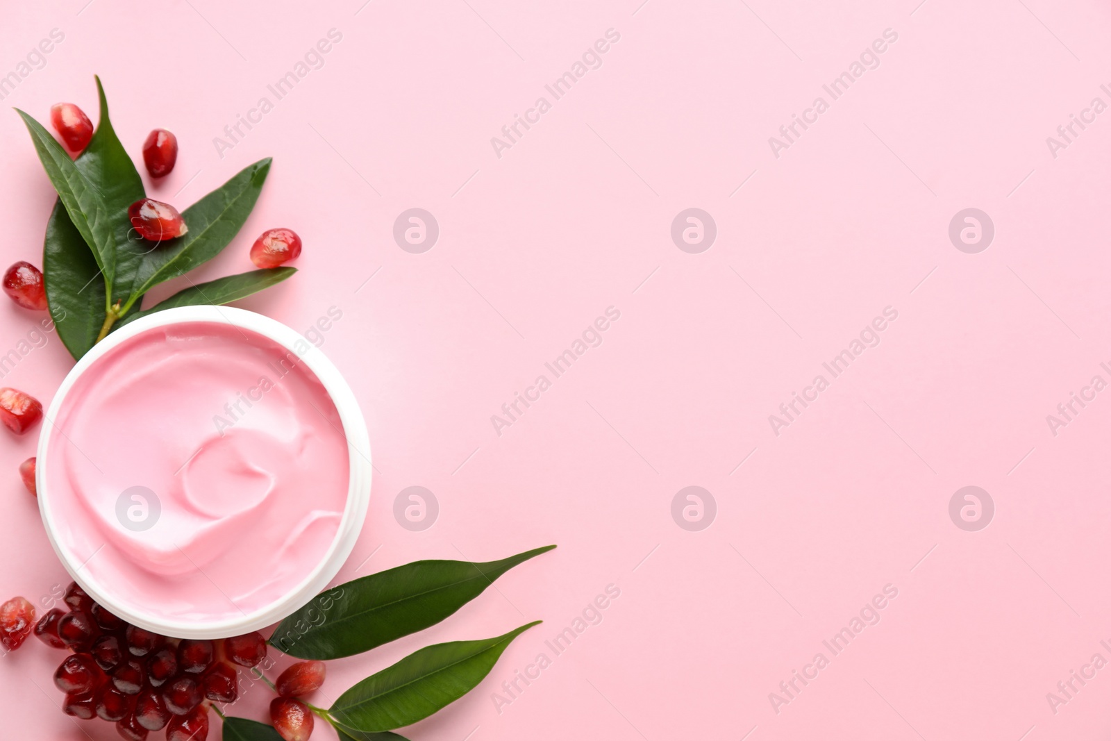 Photo of Fresh pomegranate and jar of facial mask on pink background, flat lay. Space for text
