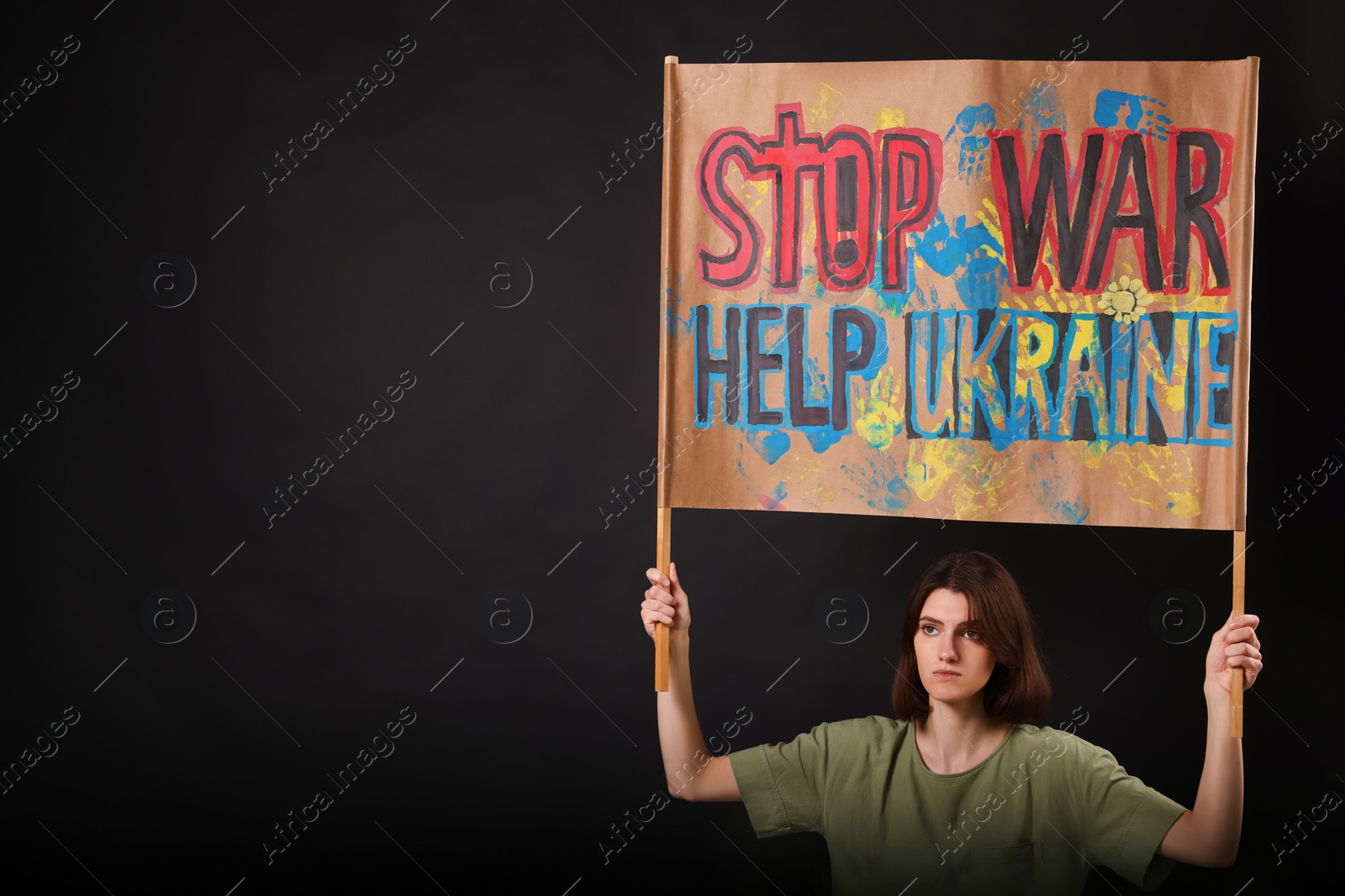 Photo of Sad woman holding placard with words Stop War Help Ukraine on black background. Space for text