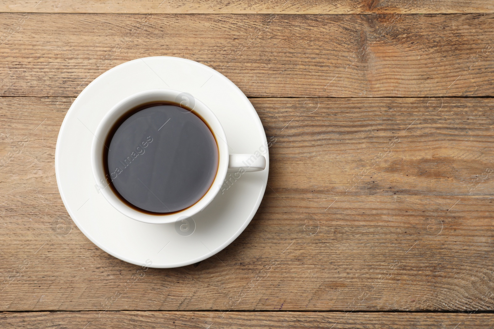 Photo of Cup of aromatic coffee on wooden table, top view. Space for text