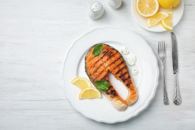 Photo of Plate with tasty salmon steak on wooden background