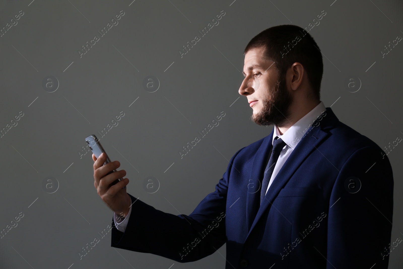 Photo of Man unlocking smartphone with facial scanner on grey background. Biometric verification