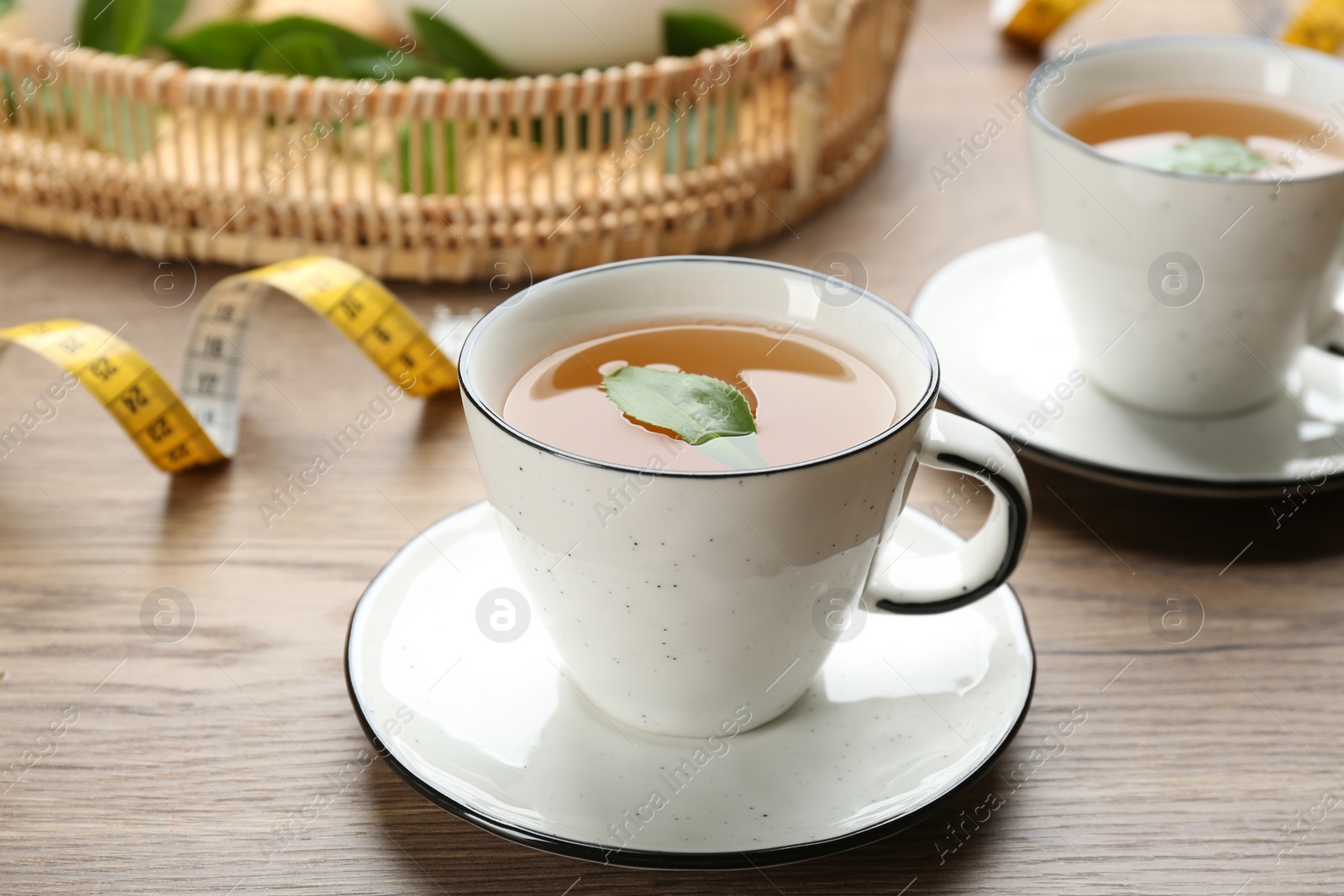 Photo of Herbal diet tea and measuring tape on wooden table