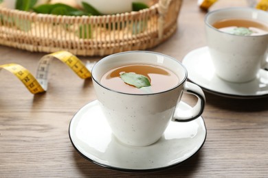 Photo of Herbal diet tea and measuring tape on wooden table