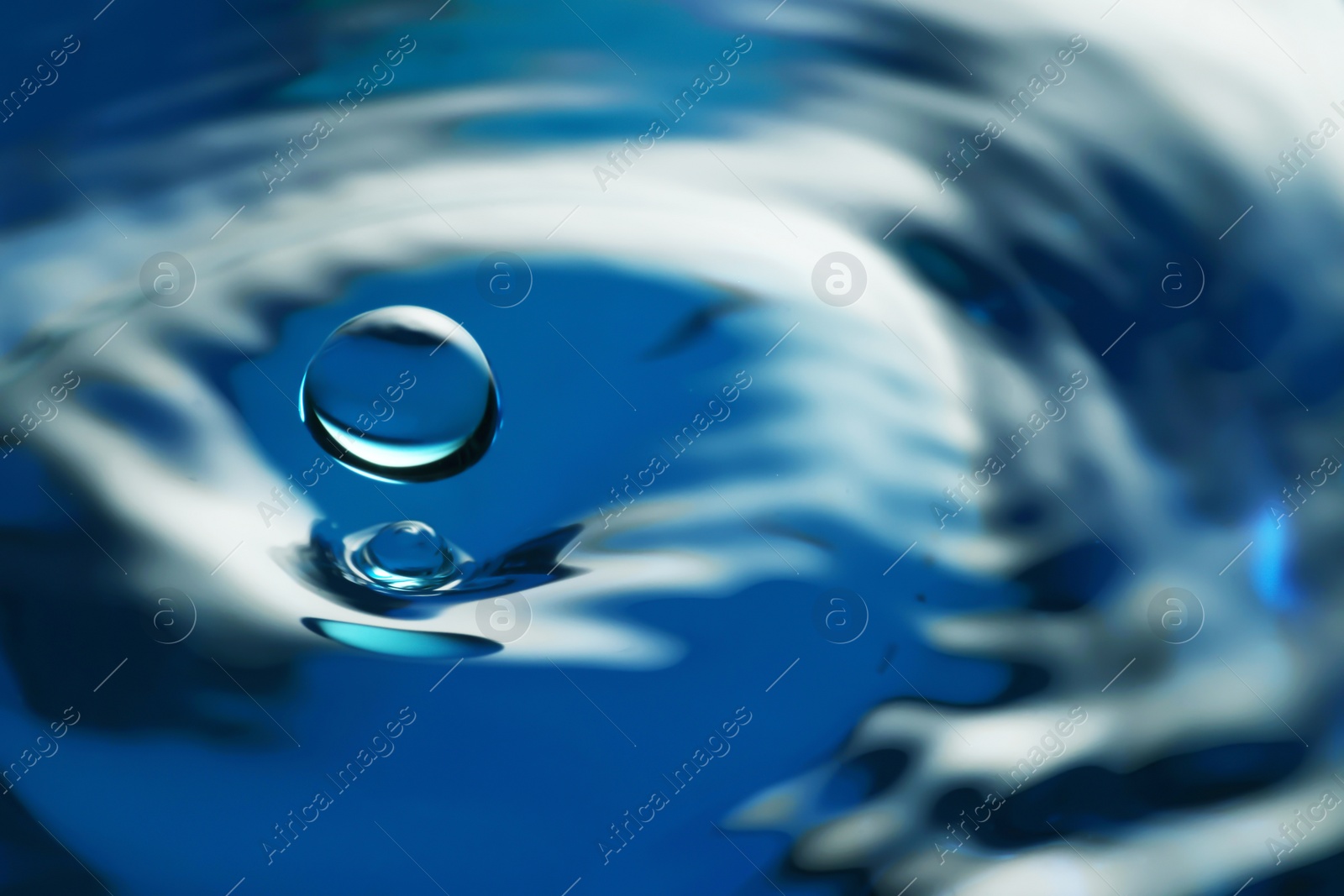 Photo of Splash of clear water with drop on blue background, closeup