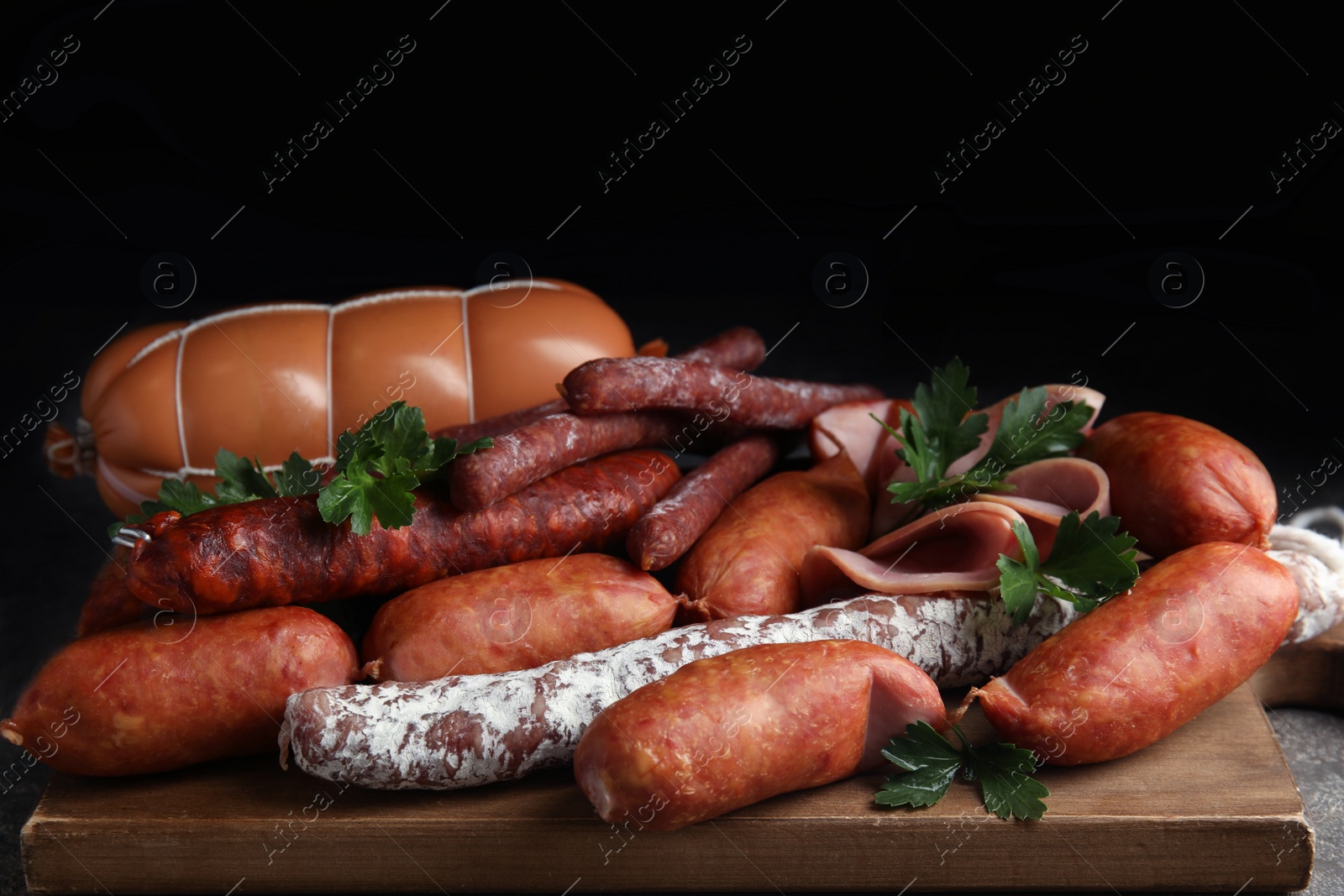 Photo of Different tasty sausages on wooden board, closeup