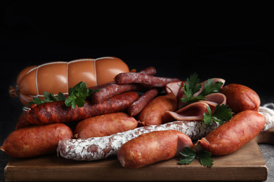 Different tasty sausages on wooden board, closeup