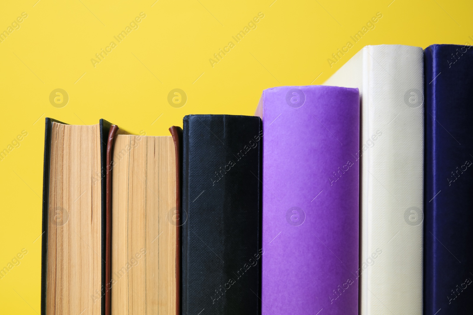 Photo of Collection of hardcover books on yellow background, closeup