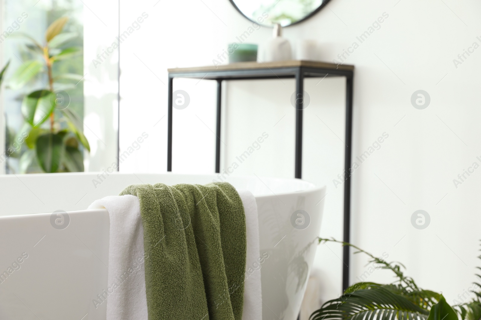 Photo of Different soft towels on tub in bathroom. Interior design