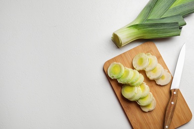 Photo of Flat lay composition with fresh raw leek on light table, space for text. Ripe onion