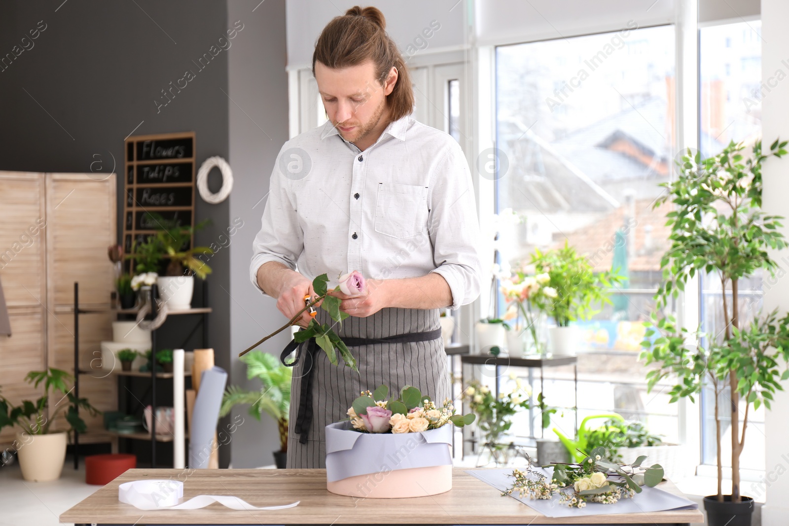 Photo of Male florist creating floral composition at workplace