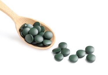 Photo of Spoon with spirulina tablets on white background