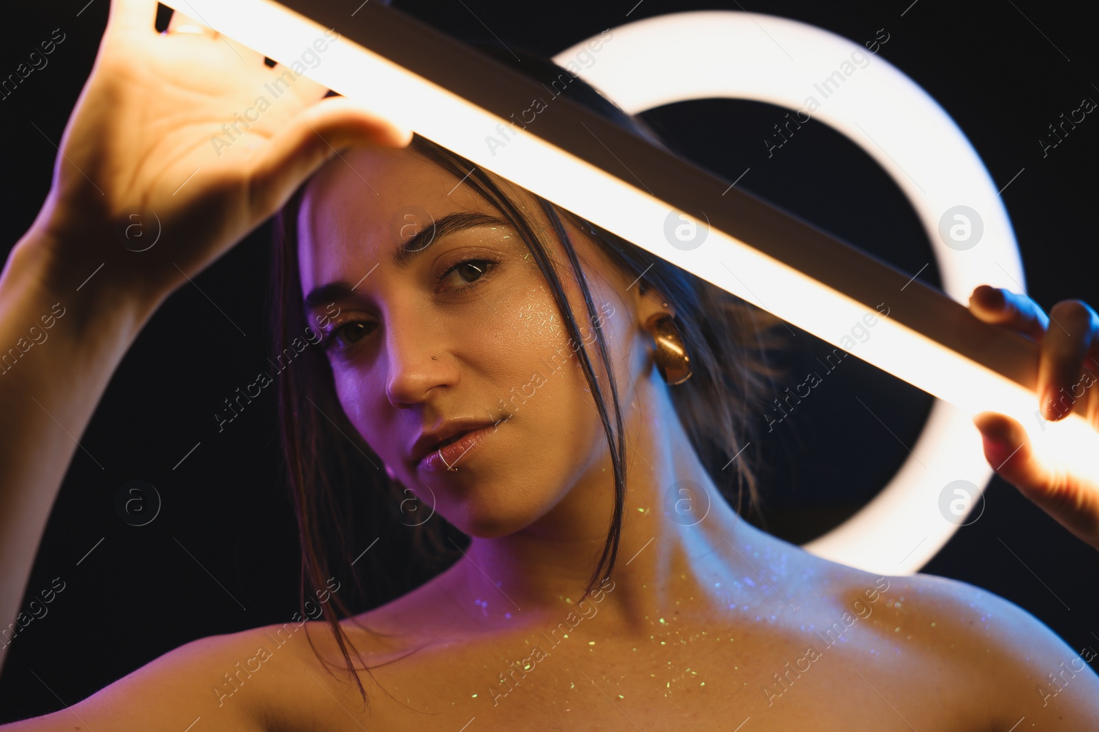 Photo of Beautiful woman with lamp on dark background in neon lights