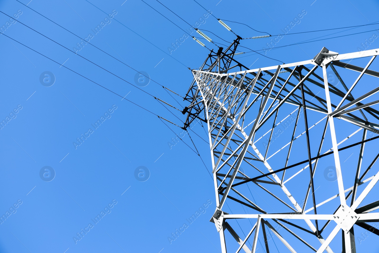 Photo of Modern high voltage tower against blue sky, low angle view