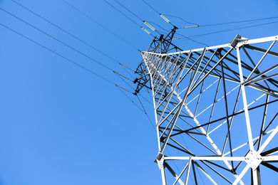 Photo of Modern high voltage tower against blue sky, low angle view