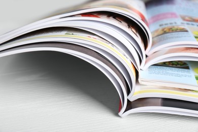 Photo of Many open magazines on white wooden table, closeup