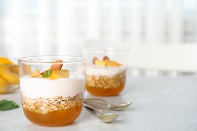 Tasty peach dessert with yogurt and granola on light table. Space for text