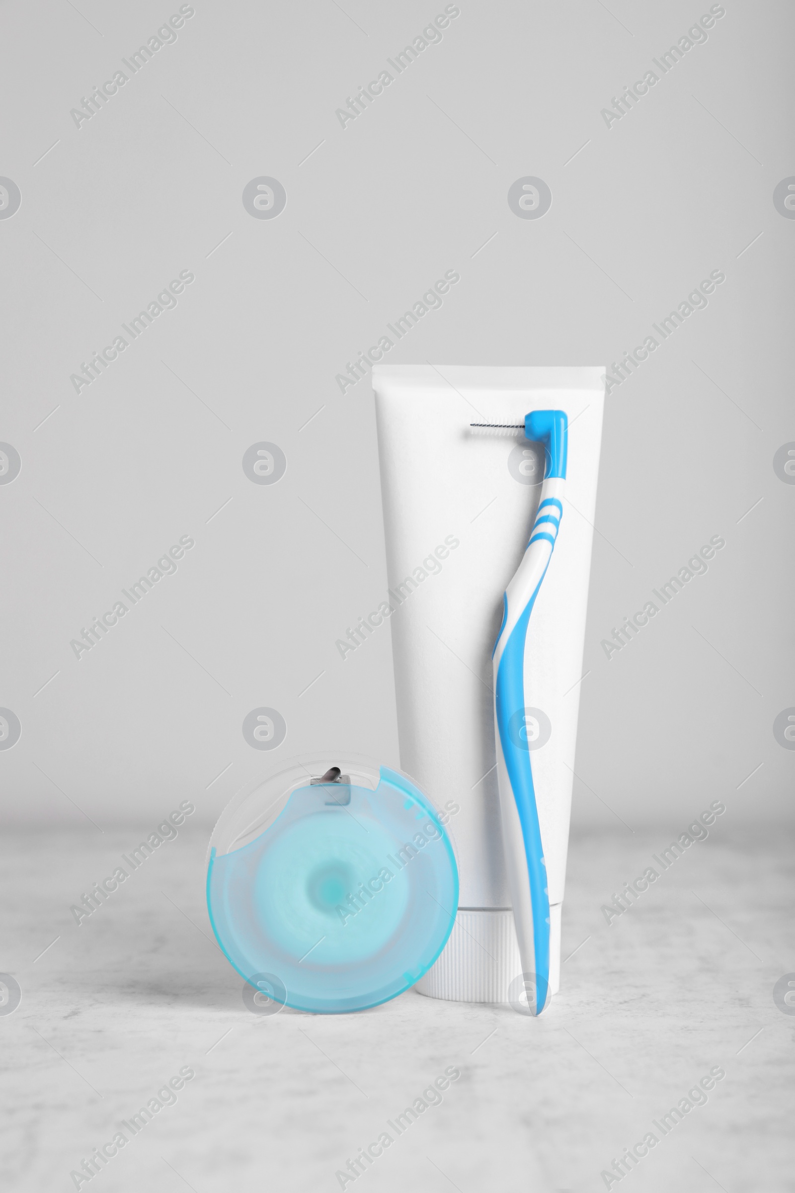 Photo of Dental floss and different teeth care products on light grey textured table