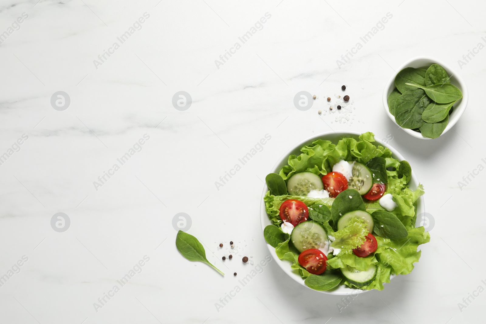 Photo of Delicious salad in bowl on white marble table, flat lay. Space for text