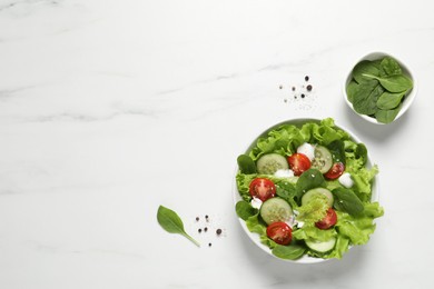 Delicious salad in bowl on white marble table, flat lay. Space for text