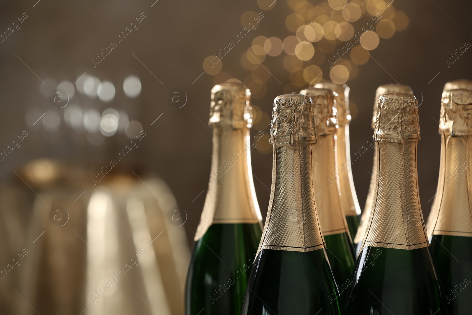 Photo of Many bottles of champagne on blurred background, closeup. Space for text