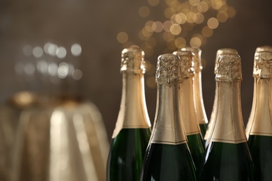 Many bottles of champagne on blurred background, closeup. Space for text