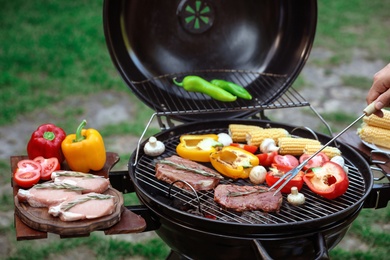 Photo of Man cooking food on barbecue grill outdoors, closeup