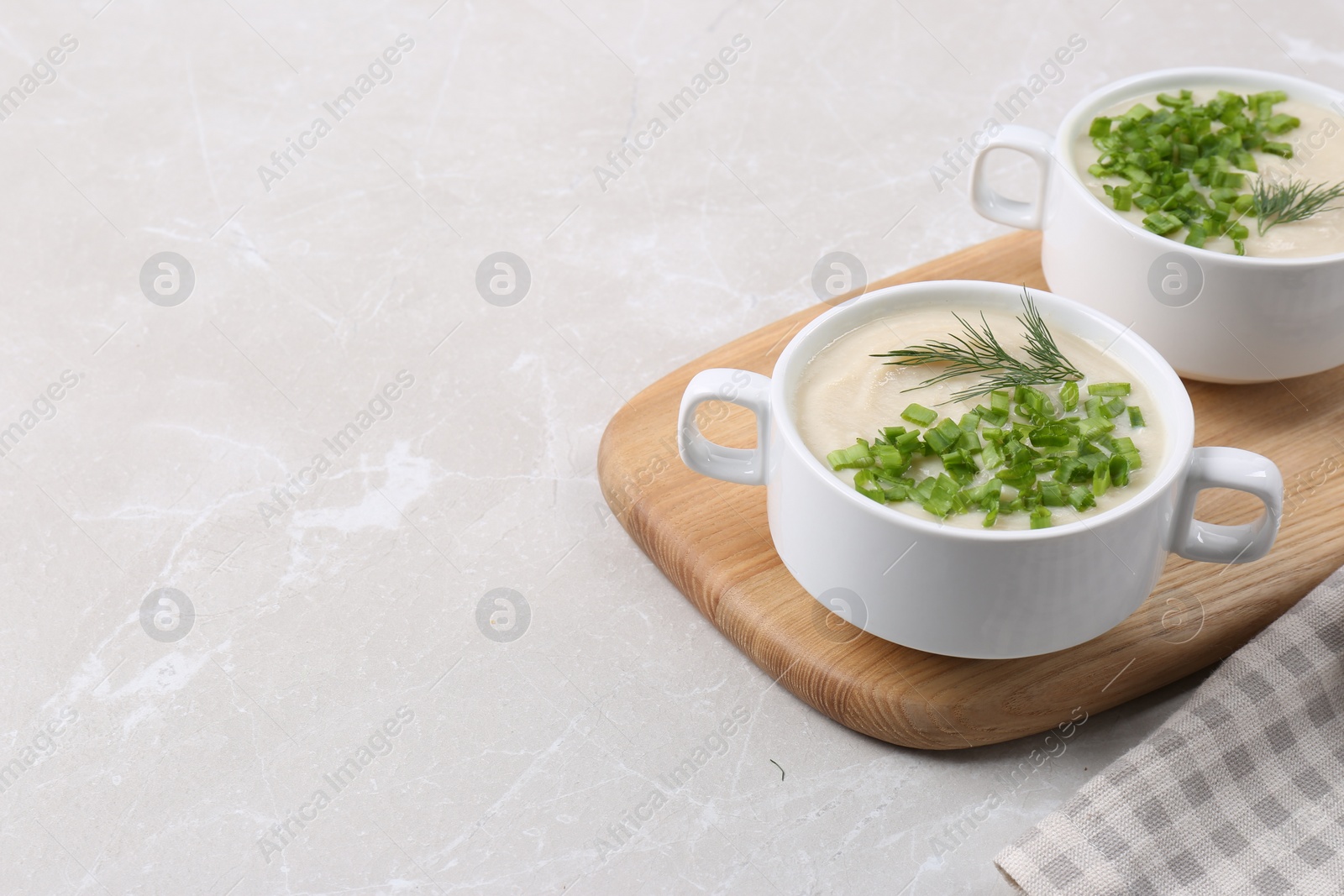 Photo of Bowls with tasty creamy soup of parsnip on light grey table, space for text