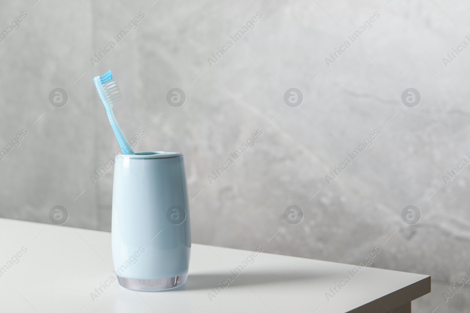 Photo of Plastic toothbrush in holder on white countertop, space for text