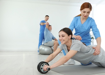 Professional physiotherapist working with female patient in rehabilitation center. Space for text