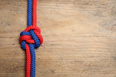 Photo of Top view of colorful ropes tied together on wooden background, space for text. Unity concept