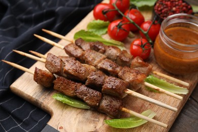 Photo of Tasty cooked marinated meat served with sauce and tomatoes on table, closeup