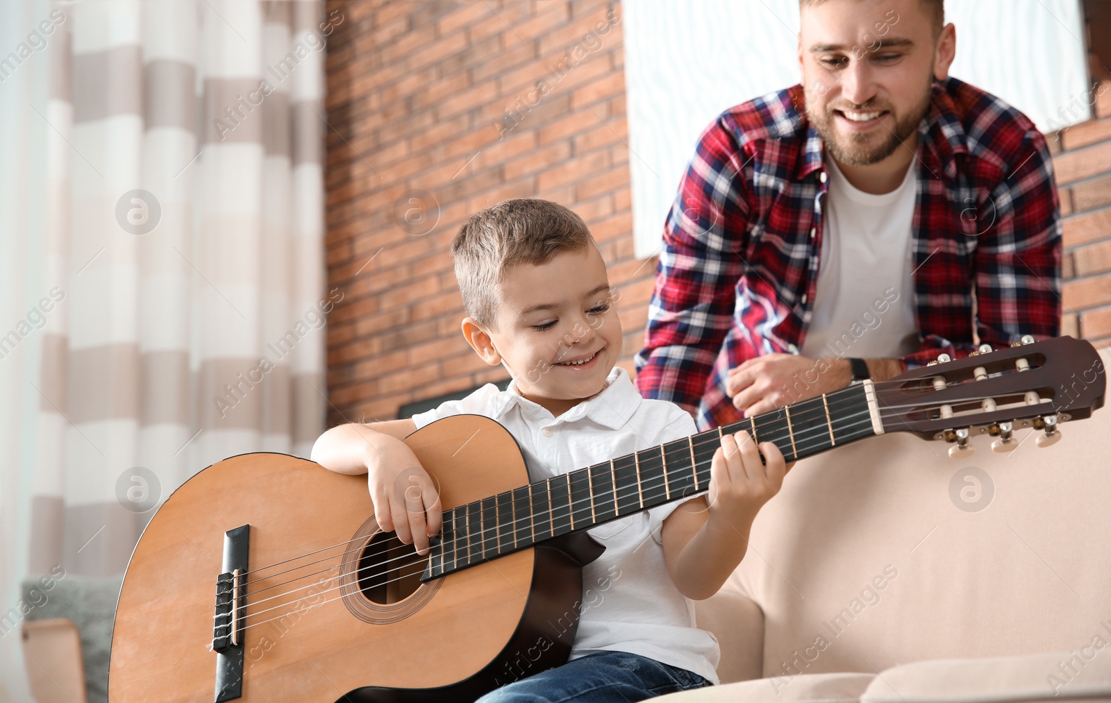 Photo of Father watching his son playing guitar at home