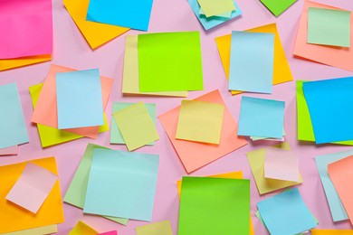 Photo of Blank colorful sticky notes on pink background, flat lay