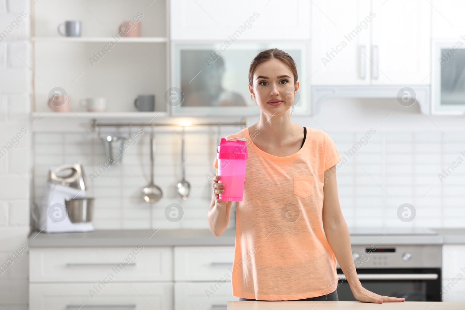 Photo of Athletic young woman with protein shake in kitchen