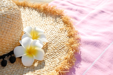 Photo of Straw hat and pink towel outdoors. Beach accessories