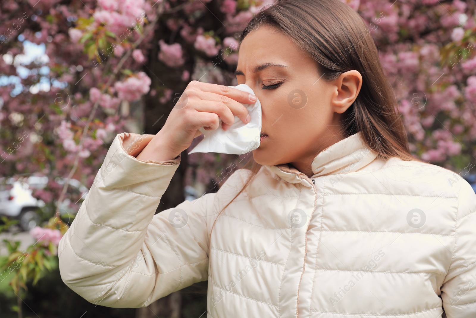 Photo of Woman suffering from seasonal pollen allergy near blossoming tree outdoors