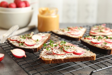 Photo of Tasty toasts with radishes, sprouts and chia seeds on cooling grate