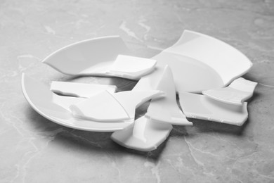 Photo of Pieces of broken ceramic plate on light grey table