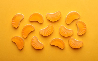 Photo of Delicious gummy candies on orange background, flat lay