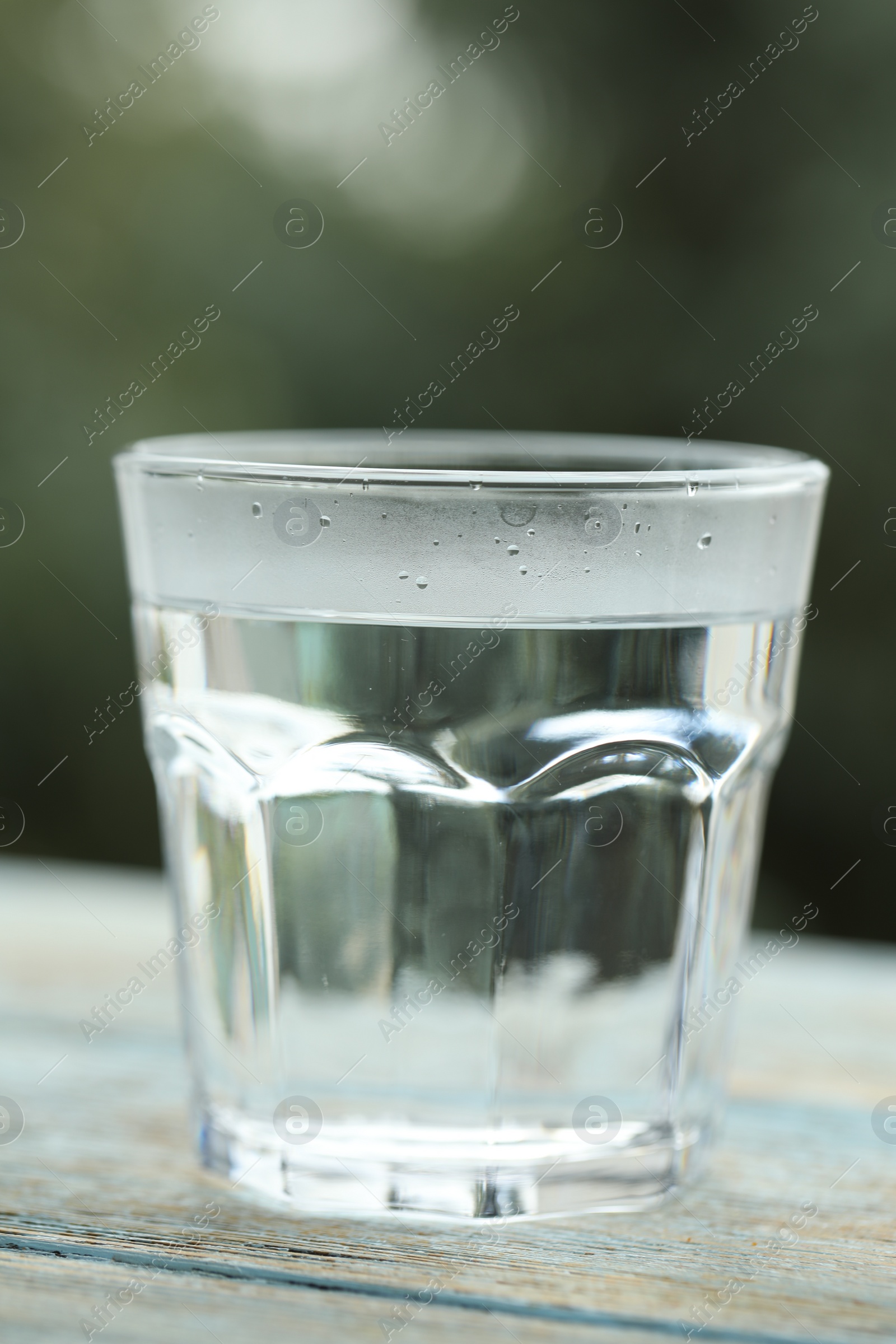 Photo of Glass of pure water on light blue wooden table against blurred background, closeup