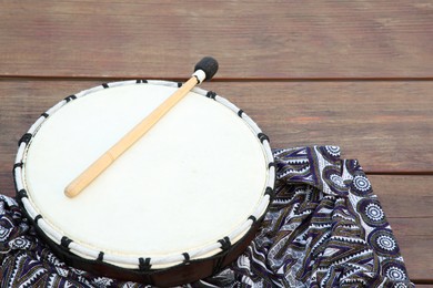 Photo of Modern drum with drumstick on wooden table. Space for text