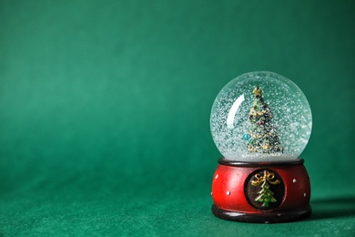 Photo of Snow globe with Christmas tree on color background. Space for text