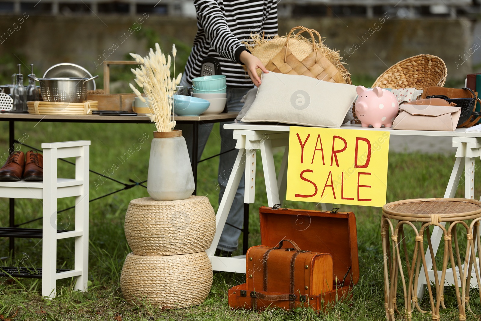 Photo of Woman near tables with different stuff on garage sale outdoors