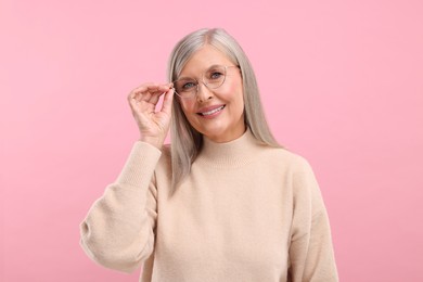 Photo of Portrait of beautiful middle aged woman in eyeglasses on pink background